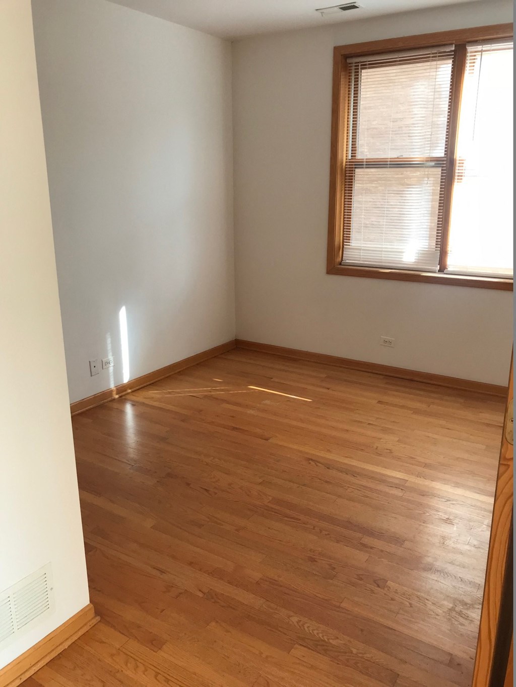 an empty room with wooden floors and a window