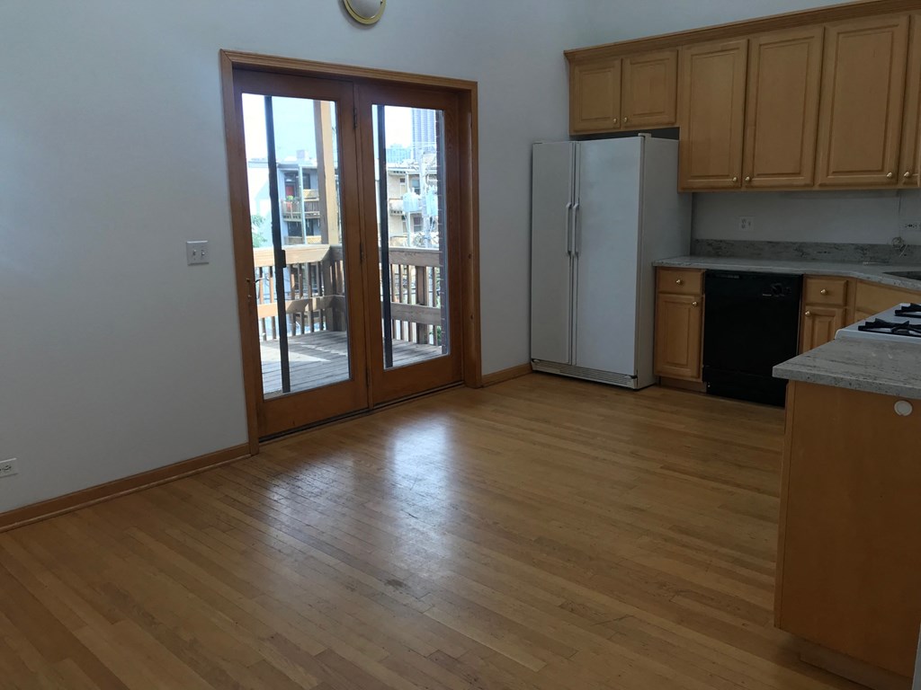 an empty living room with wood floors and a door to a balcony