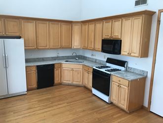an empty kitchen with wood flooring and wooden cabinets