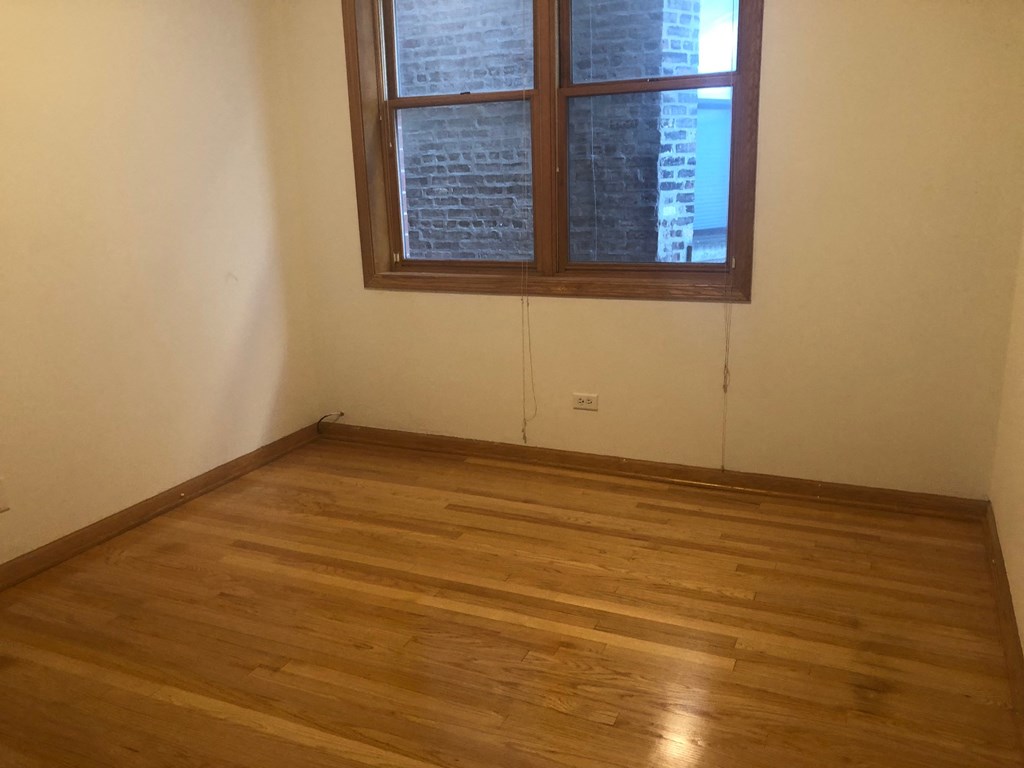 an empty room with a window and wooden floors
