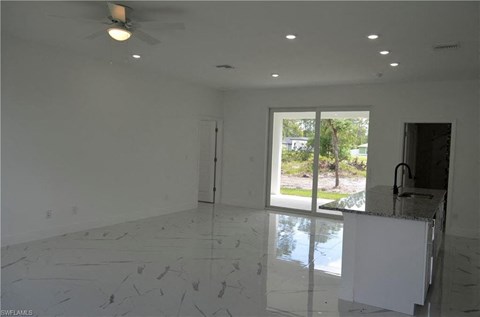 an empty living room with a marble floor and a sliding glass door