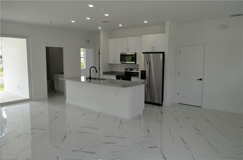 a white kitchen with a large island and a refrigerator