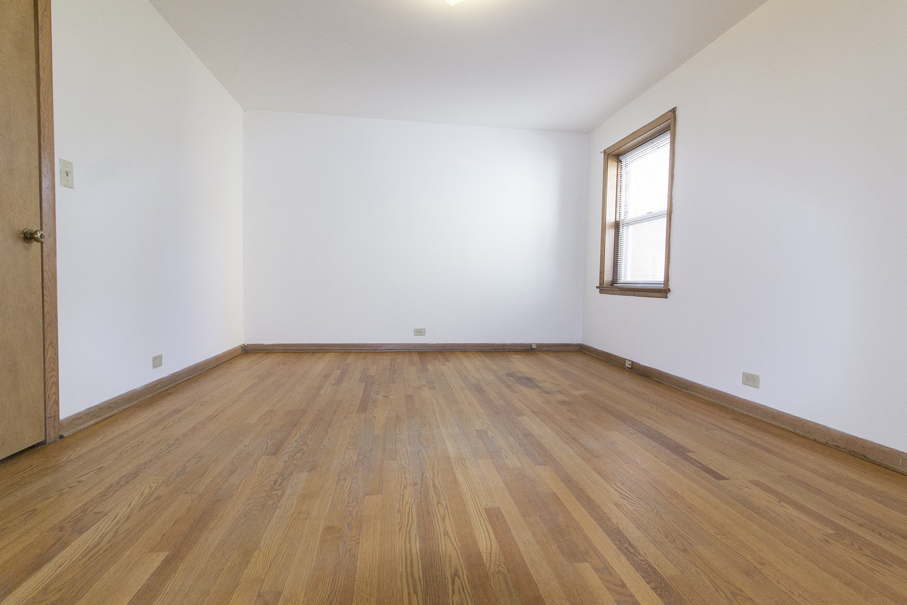an empty room with wooden floors and a window