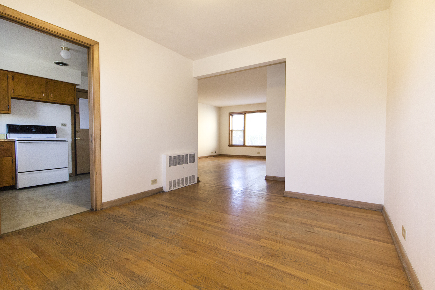 an empty living room and kitchen with white walls and wood floors