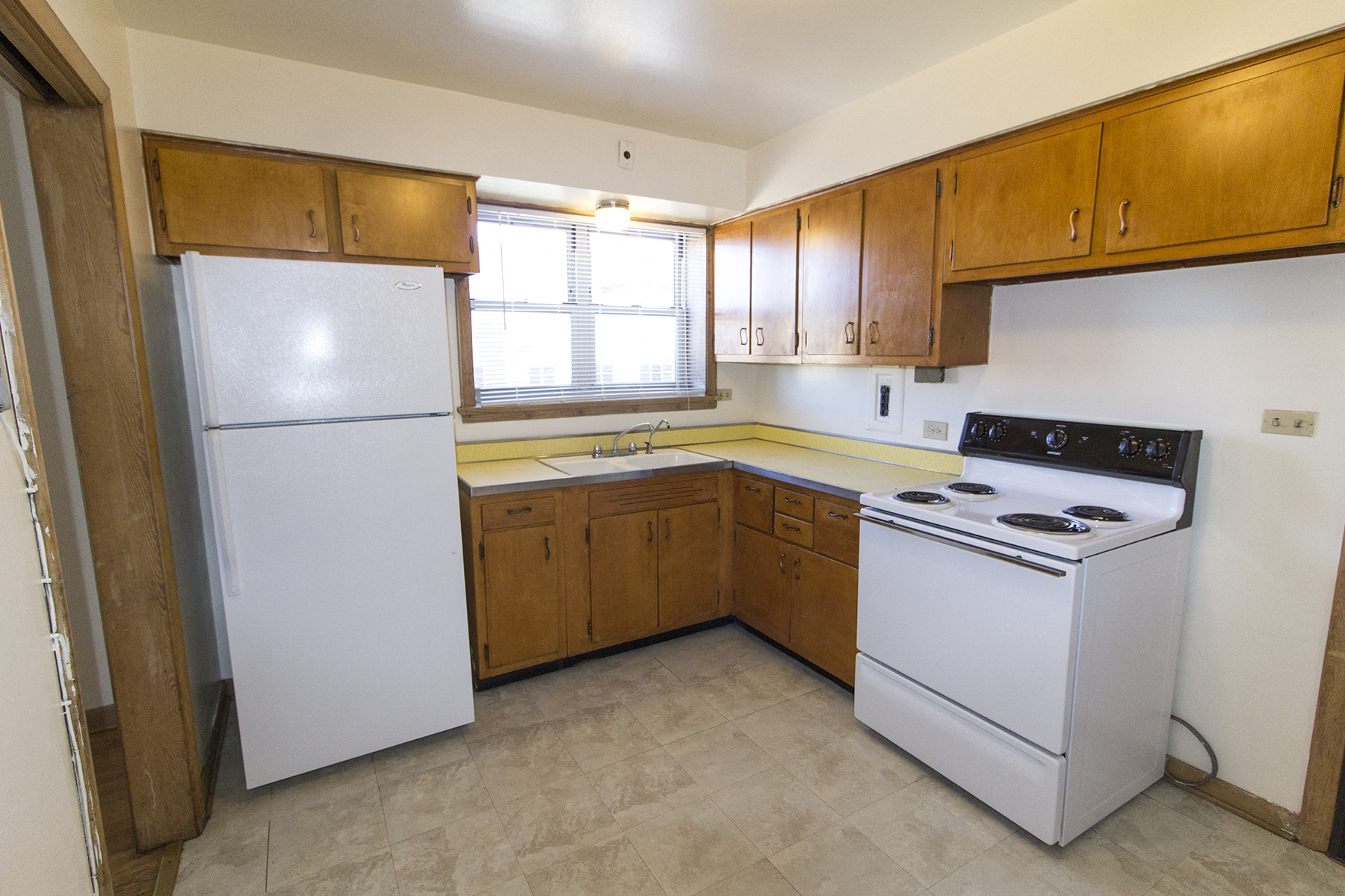 an empty kitchen with white appliances and wooden cabinets