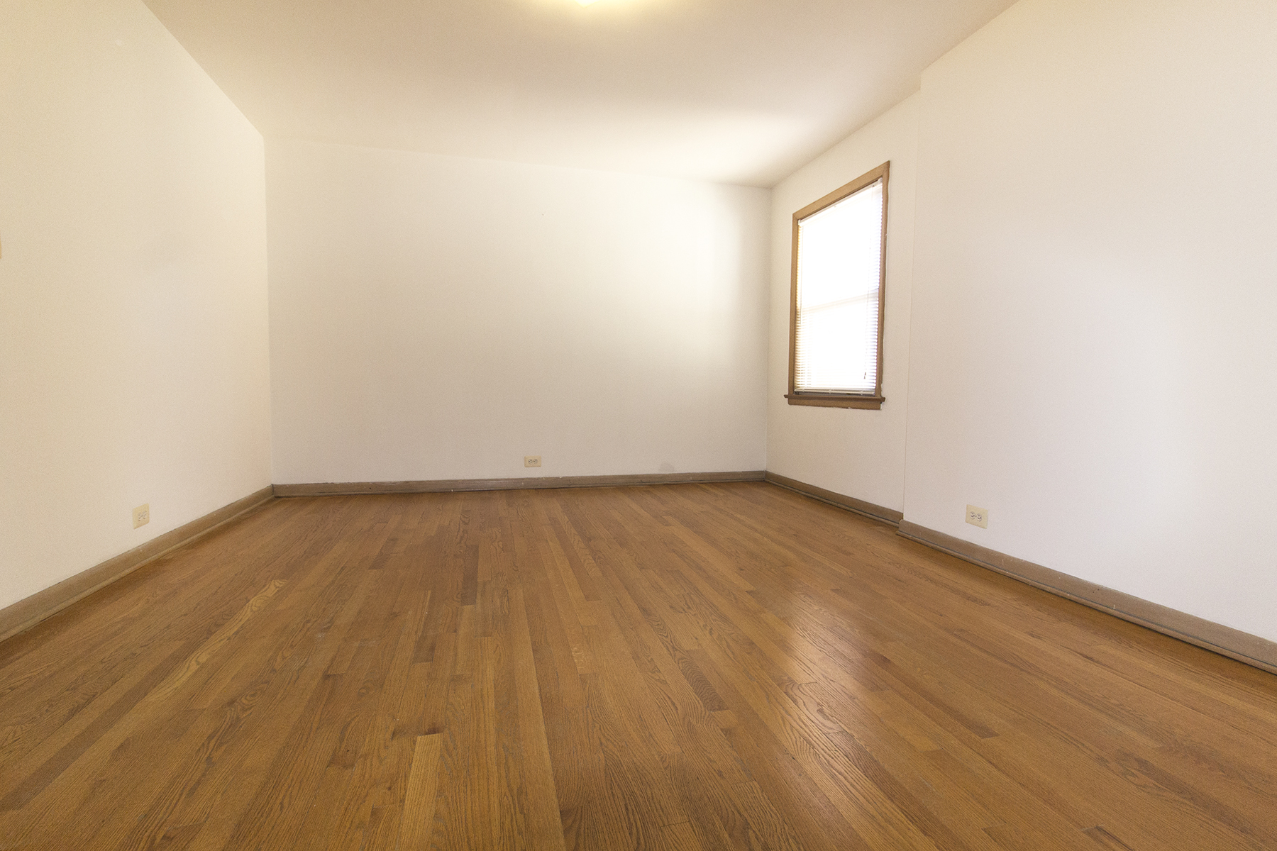 an empty room with wooden floors and a window