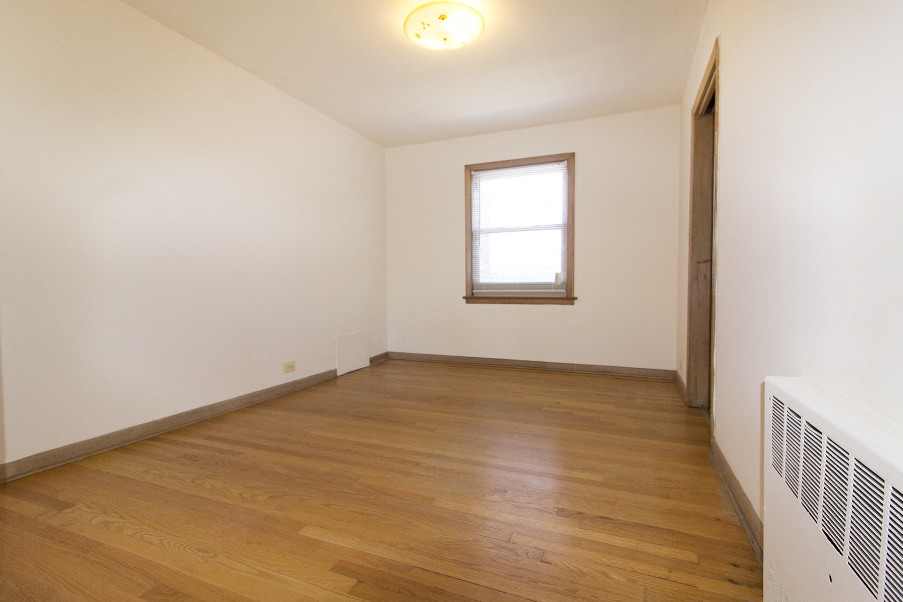 an empty room with wooden floors and a window