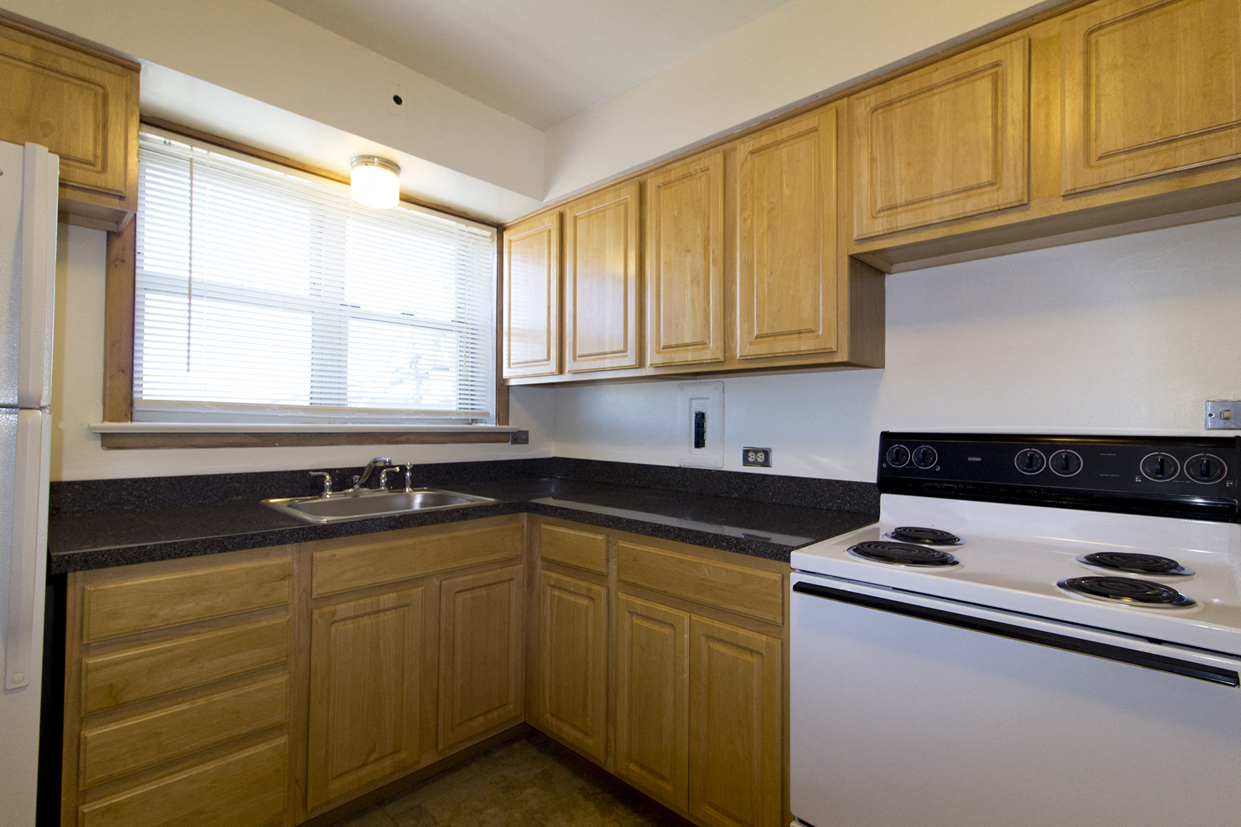 a kitchen with black counter tops and wooden cabinets