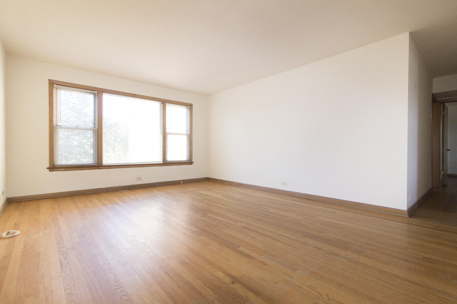 an empty living room with wood floors and a window