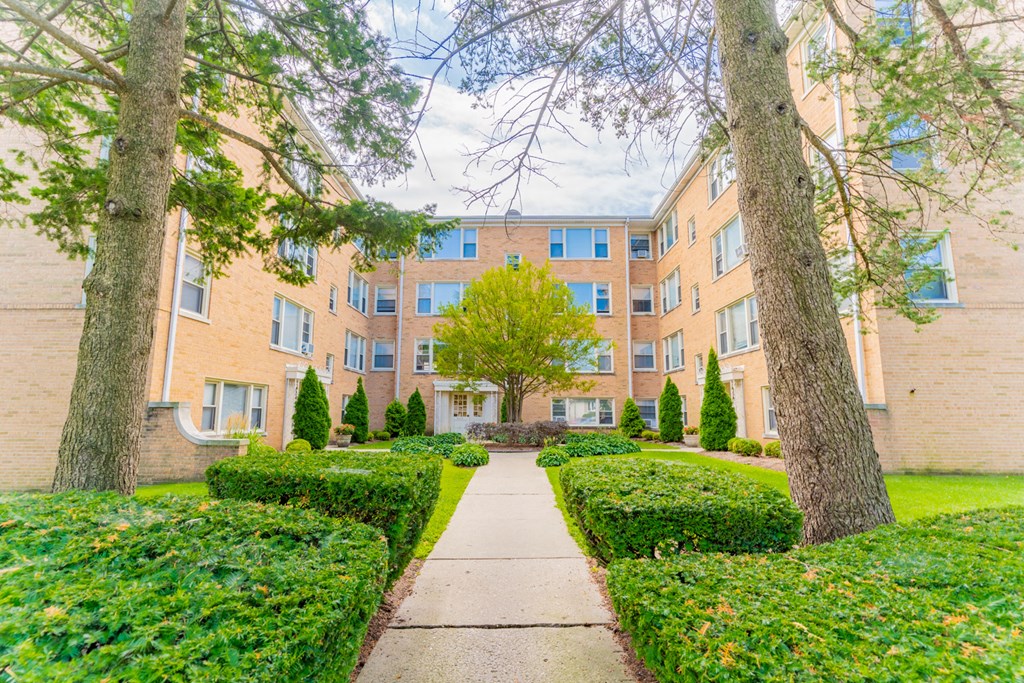 an exterior view of a building with a sidewalk and trees