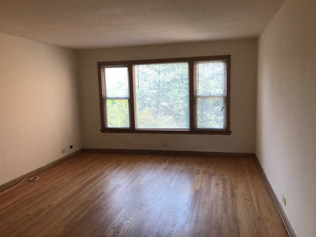 an empty room with a window and wooden floors
