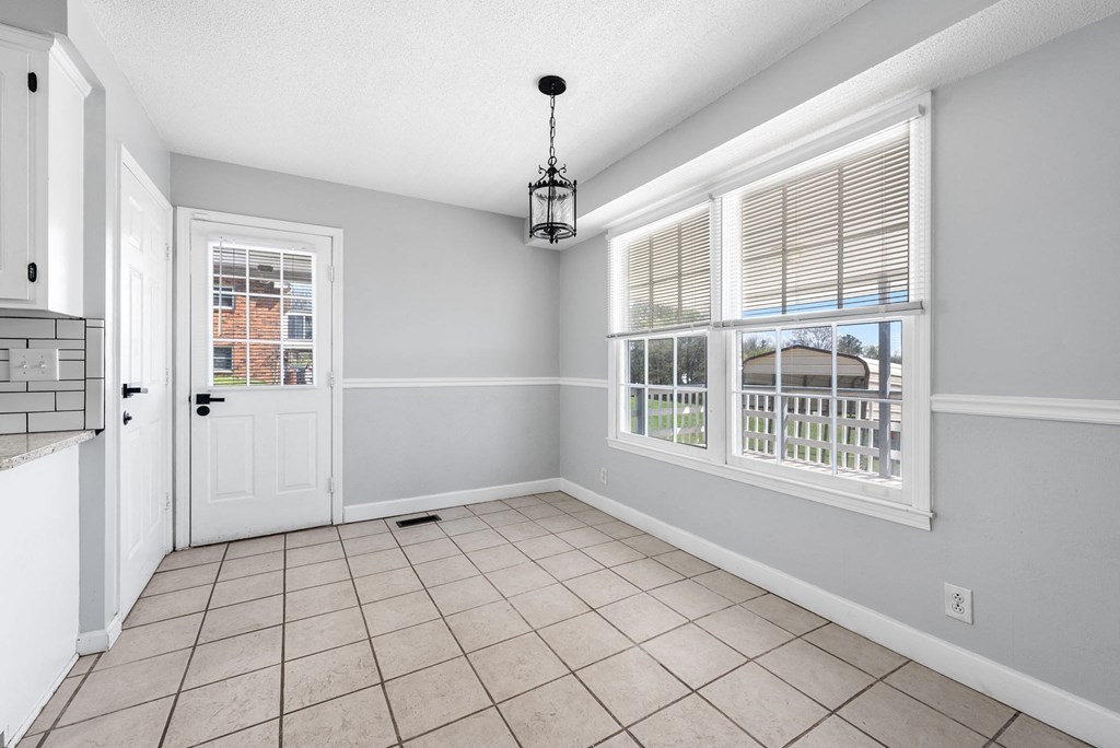 the dining room is spacious and has a large window and a door to the kitchen