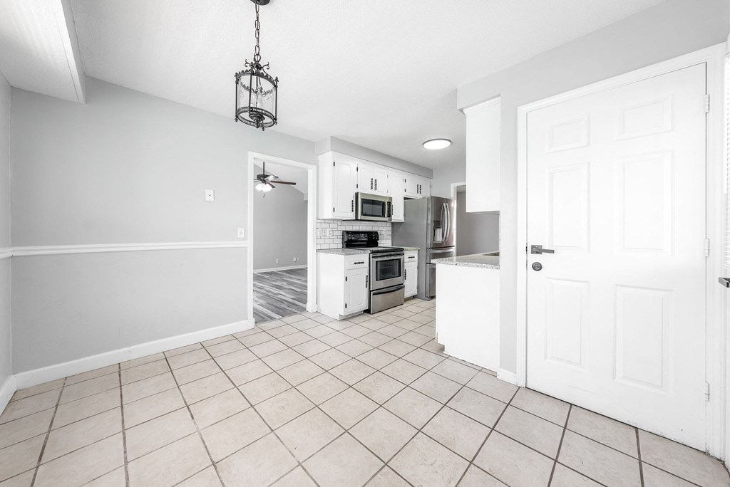 an empty kitchen and living room with a door open