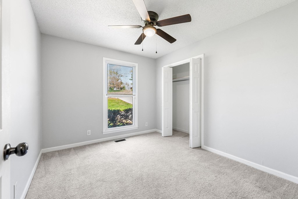 an empty room with a ceiling fan and a window