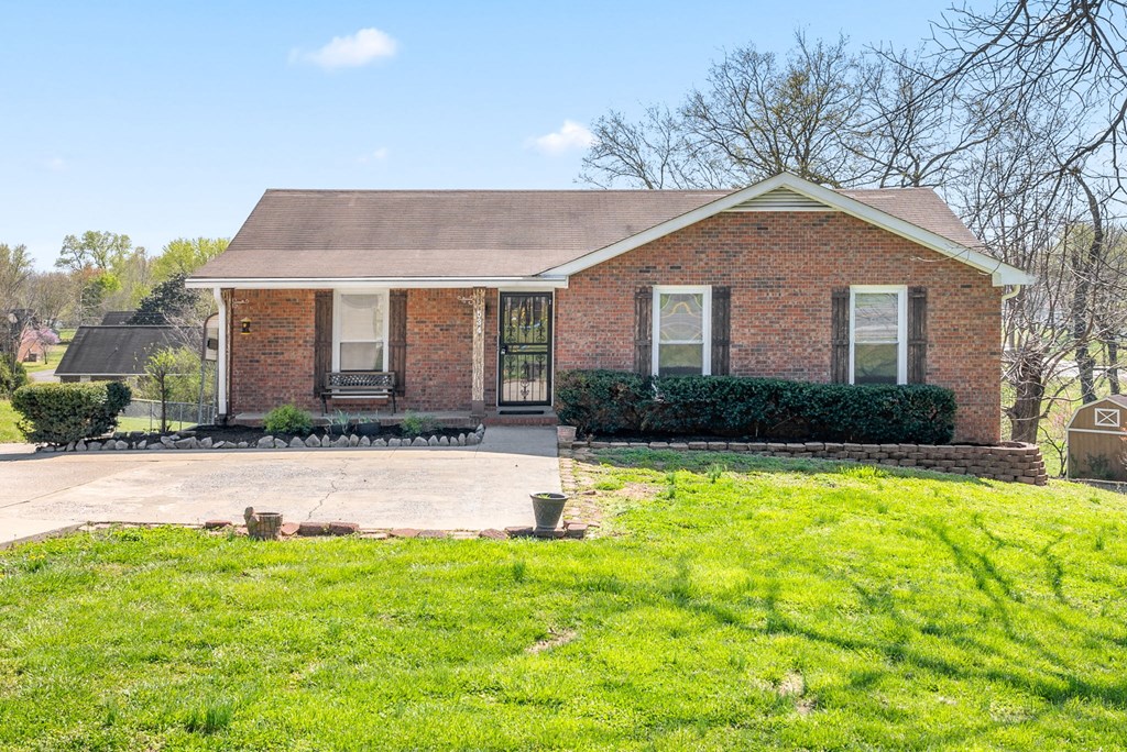 the front of a brick house with a yard and a driveway
