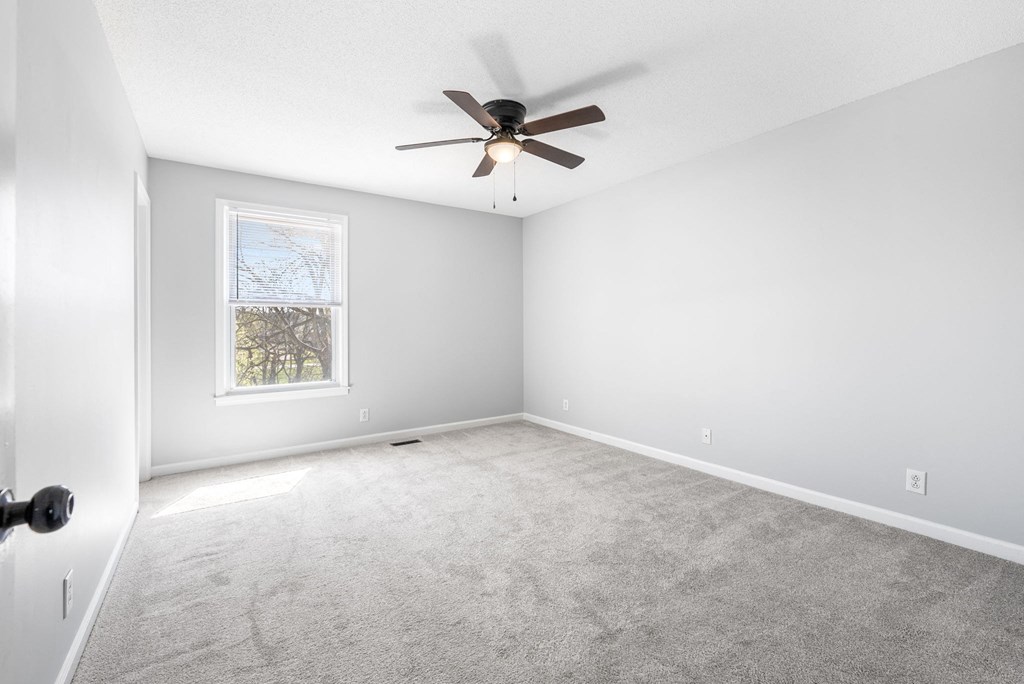 an empty living room with a ceiling fan and a window