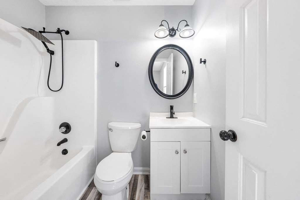 a white bathroom with a white toilet and a bath tub