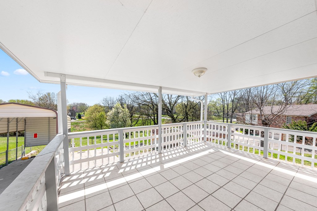 the view from the porch of a house with white railings and a white roof