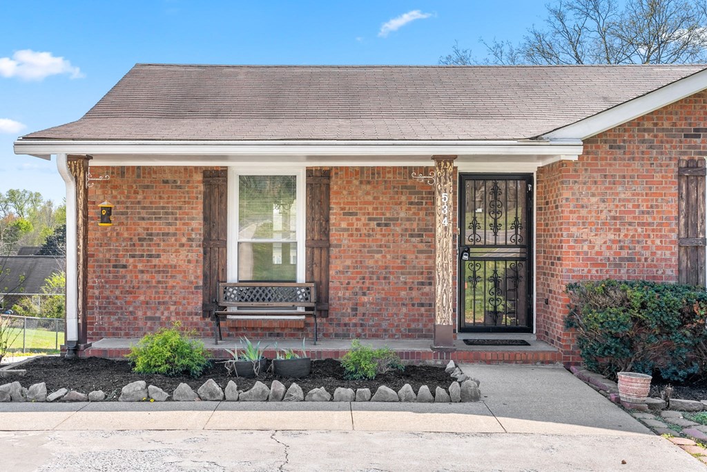the front of a brick house with two windows and a sidewalk