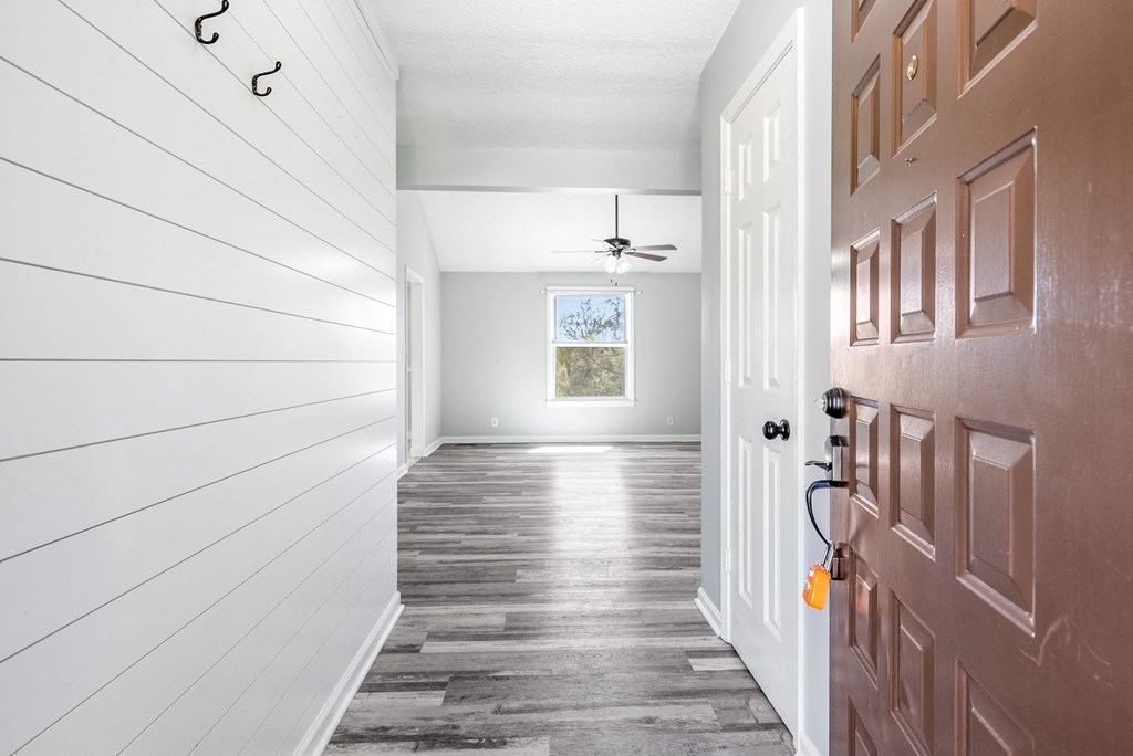 the entrance to a home with a wooden floor and a brown door
