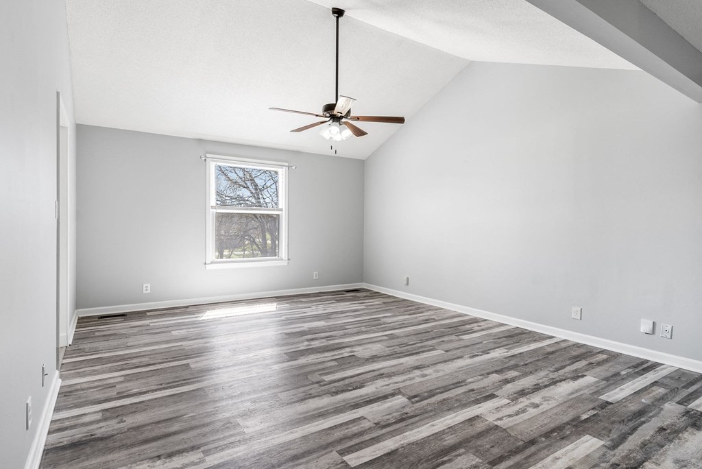 an empty living room with a ceiling fan and a window