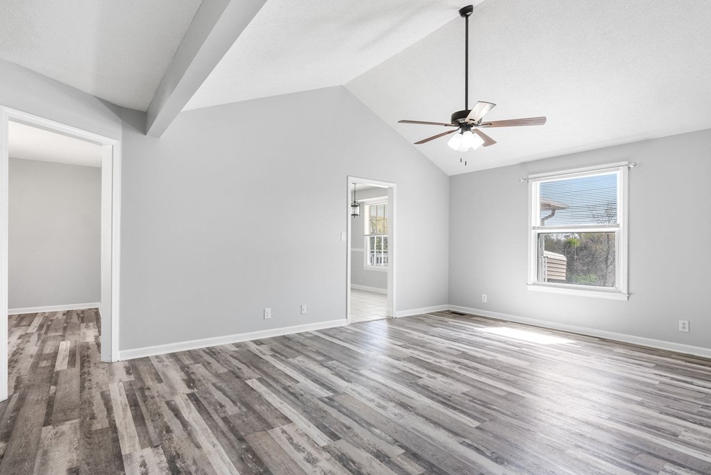 an empty living room with a ceiling fan and a window