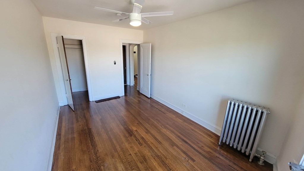 a room with white walls and wood floors and a radiator