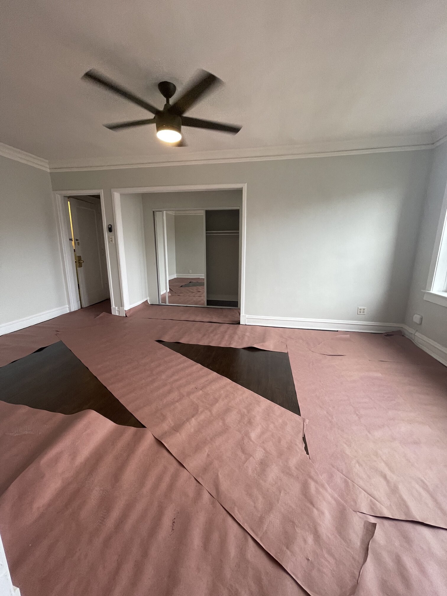 an empty living room with wood floors and a ceiling fan
