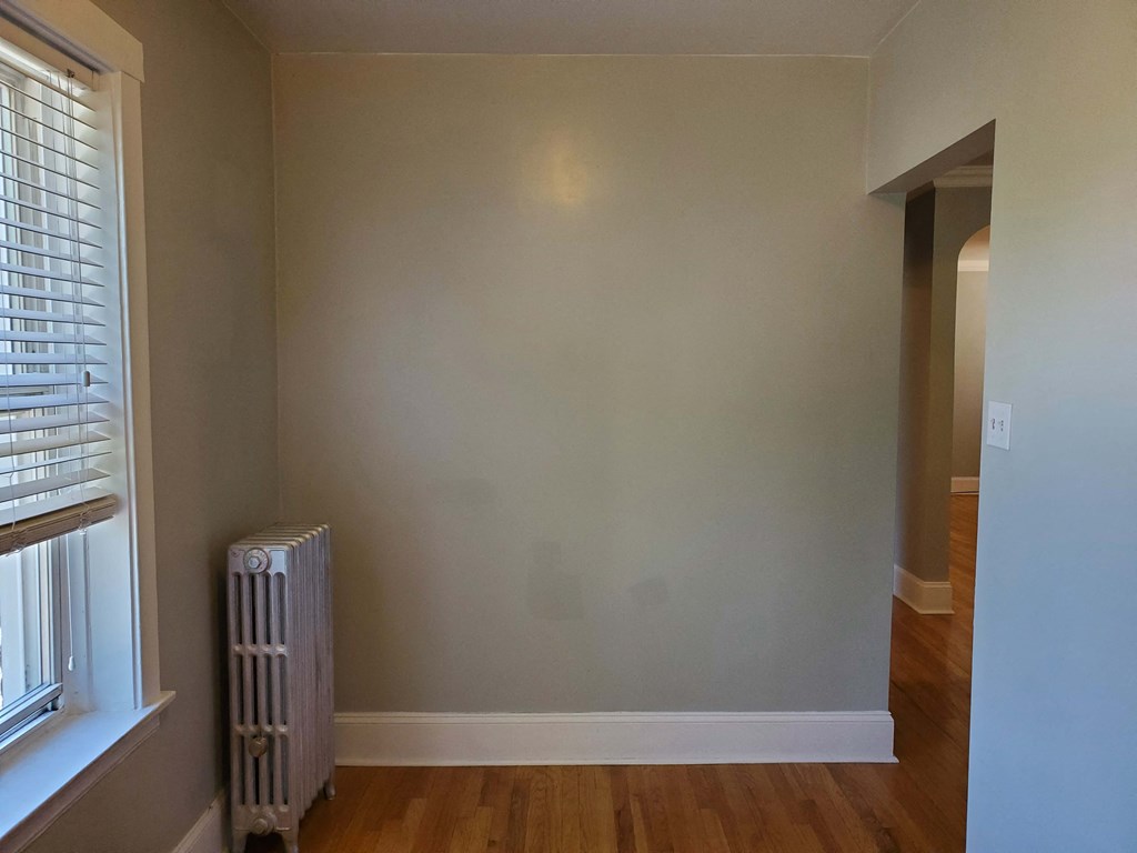 a blank wall in a room with a radiator and a window