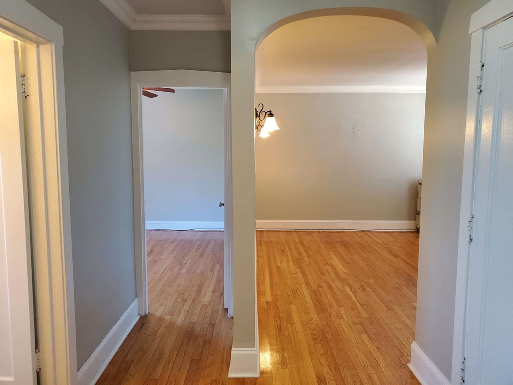 a living room and dining room with a hard wood floor and an arched doorway
