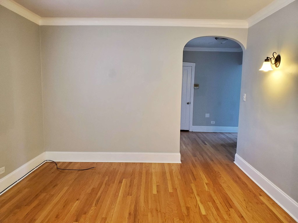a living room with a wooden floor and an arched doorway