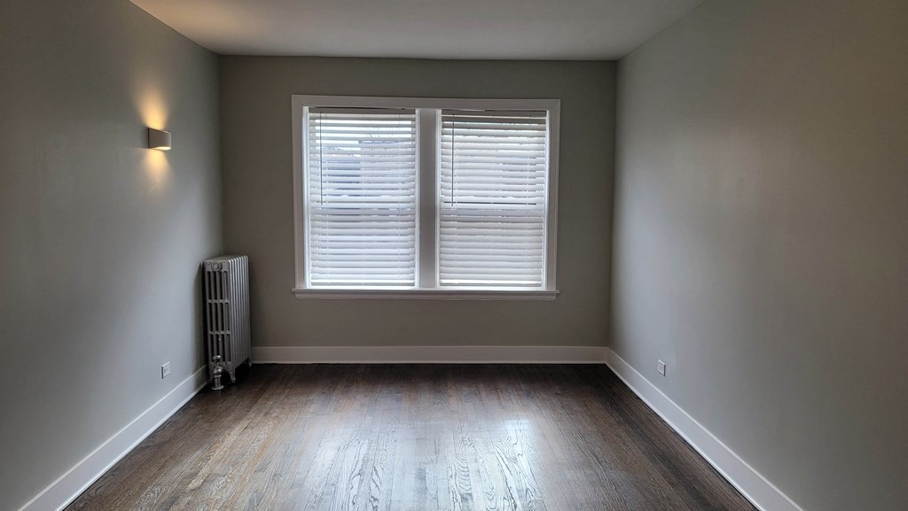 a empty room with a window and wood floors