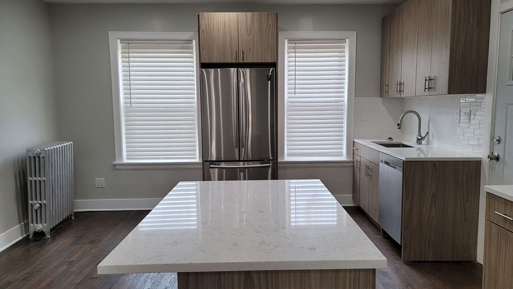 a kitchen with a large island and a stainless steel refrigerator