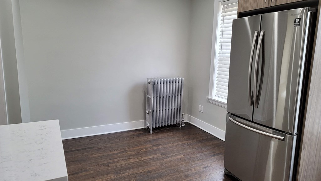 a kitchen with a refrigerator and a radiator in the corner