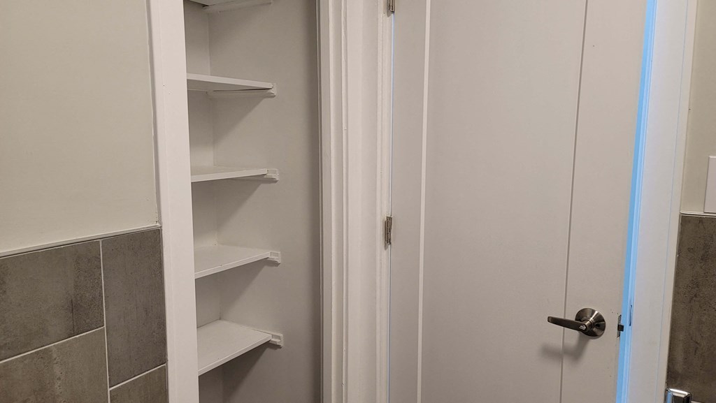 a small bathroom with a white closet with shelves