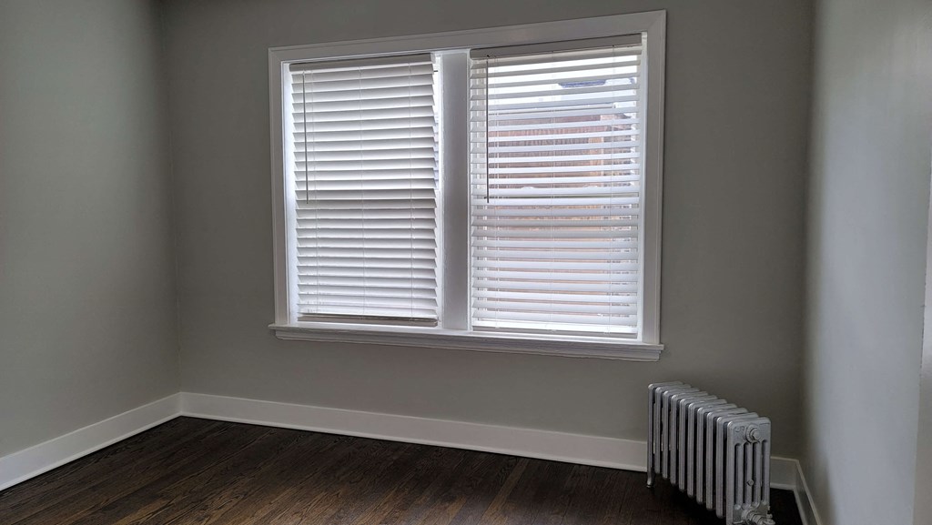 a room with a radiator and a window with white shutters