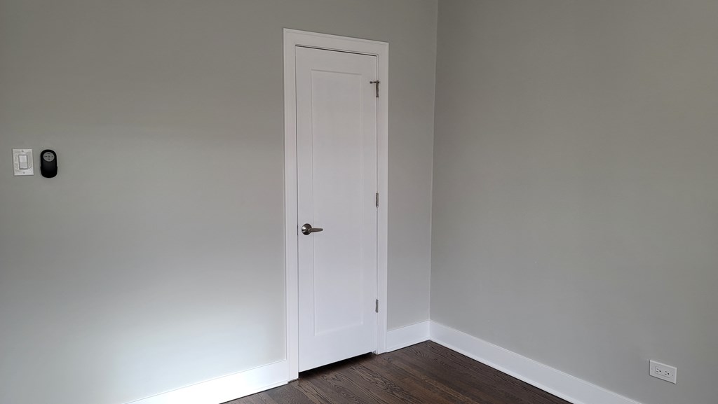 a door in a room with a wooden floor and a white wall with a door