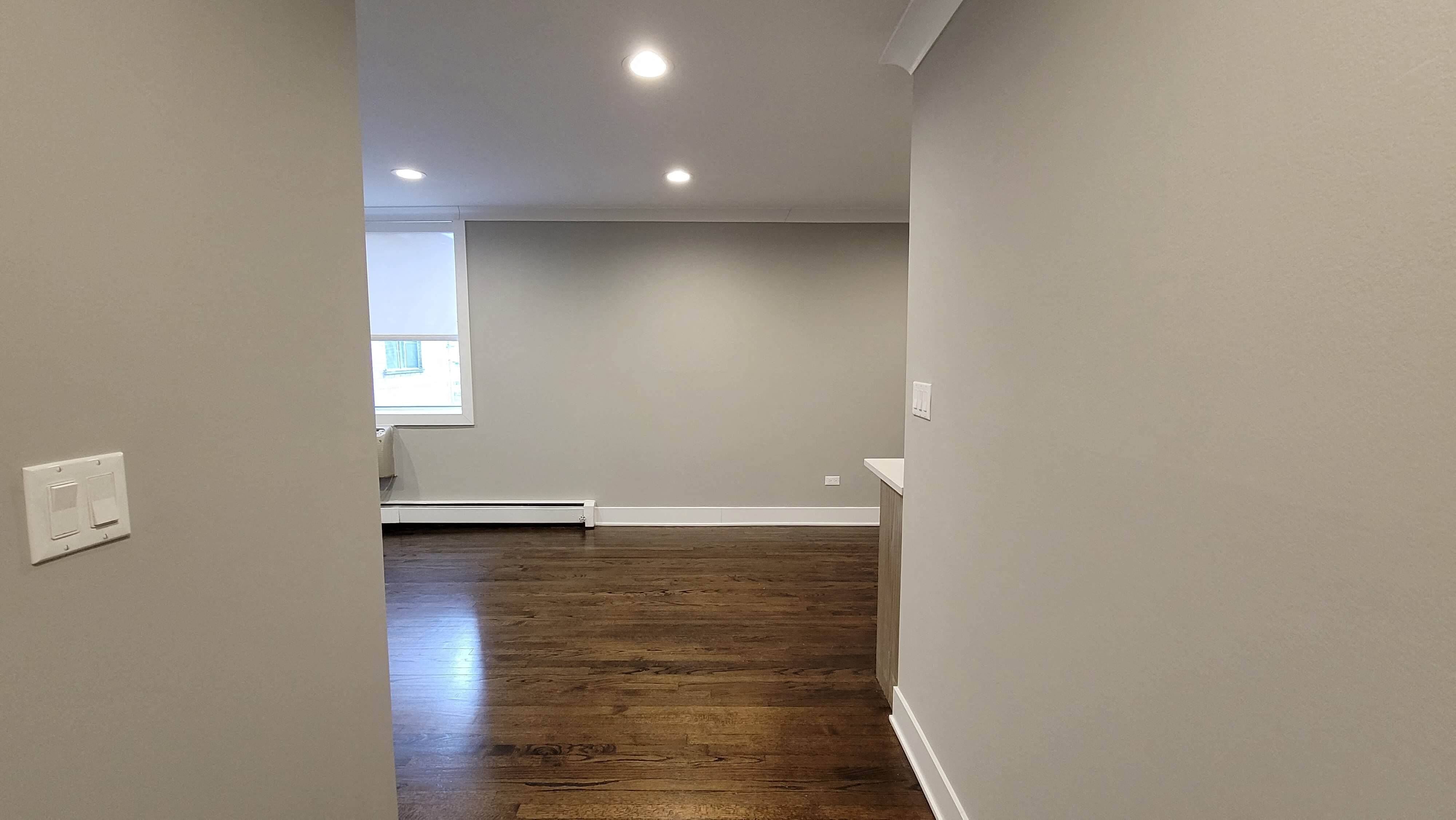 a living room with white walls and a wood floor
