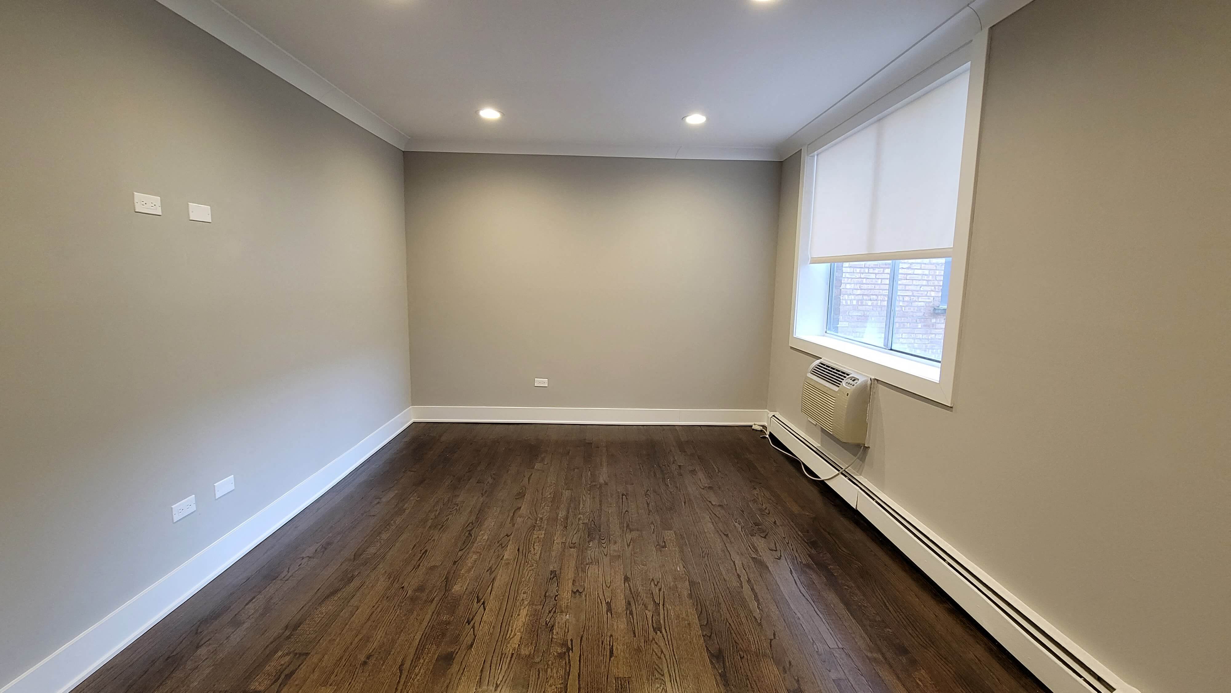 a empty living room with wood floors and a window