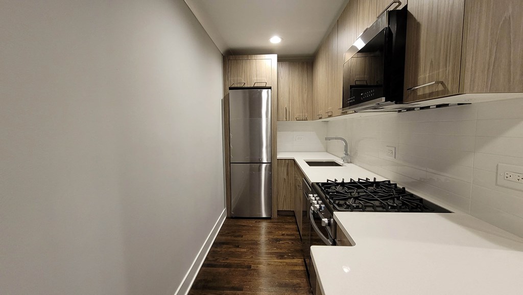 a kitchen with white countertops and a stainless steel refrigerator