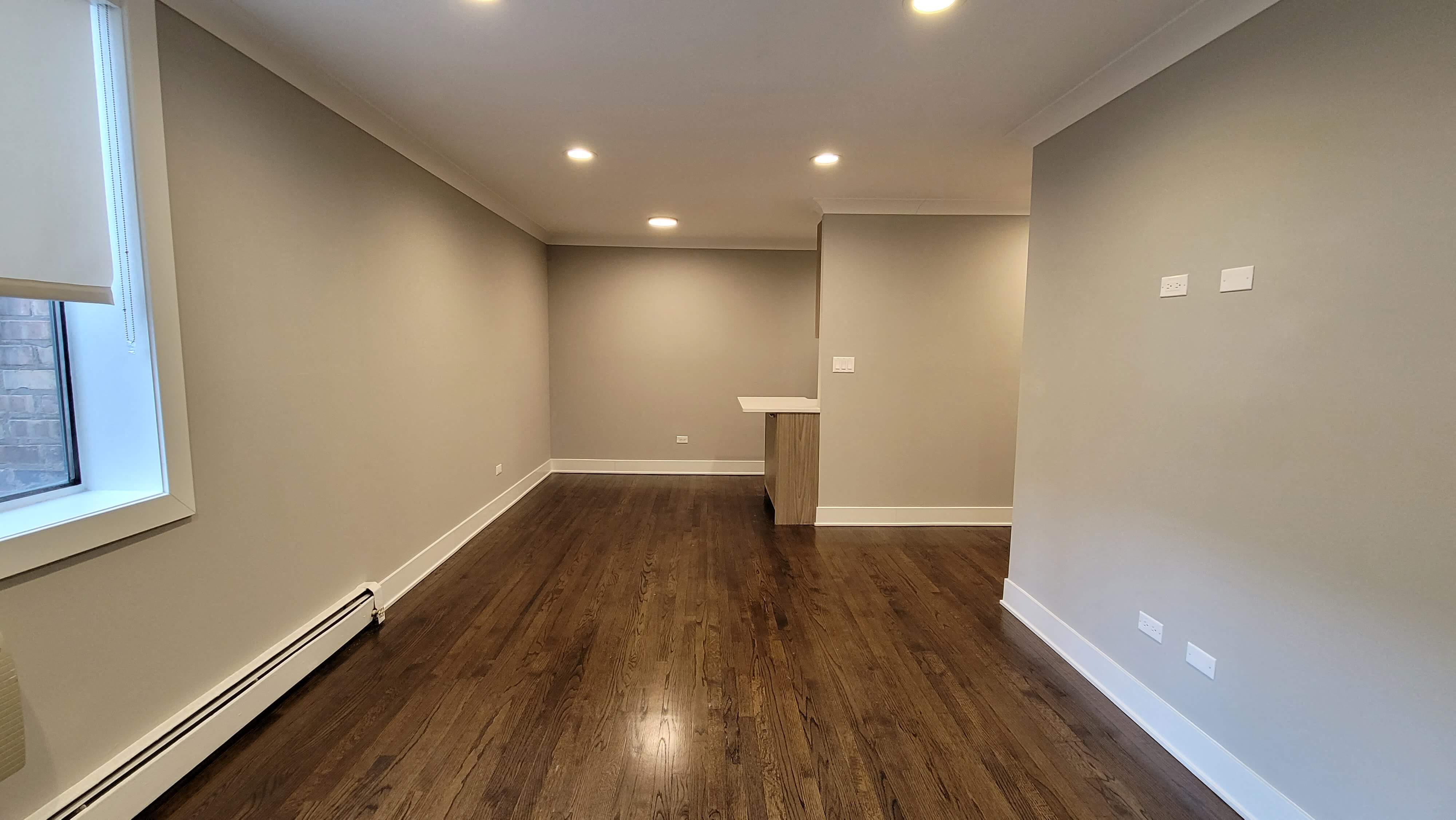 a empty living room with wood floors and a window