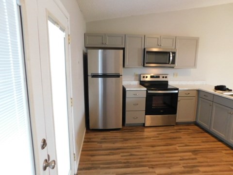 A kitchen with a stainless steel refrigerator, microwave, and oven.