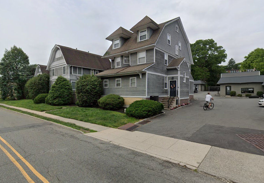 a man riding a bike down a street in front of a house