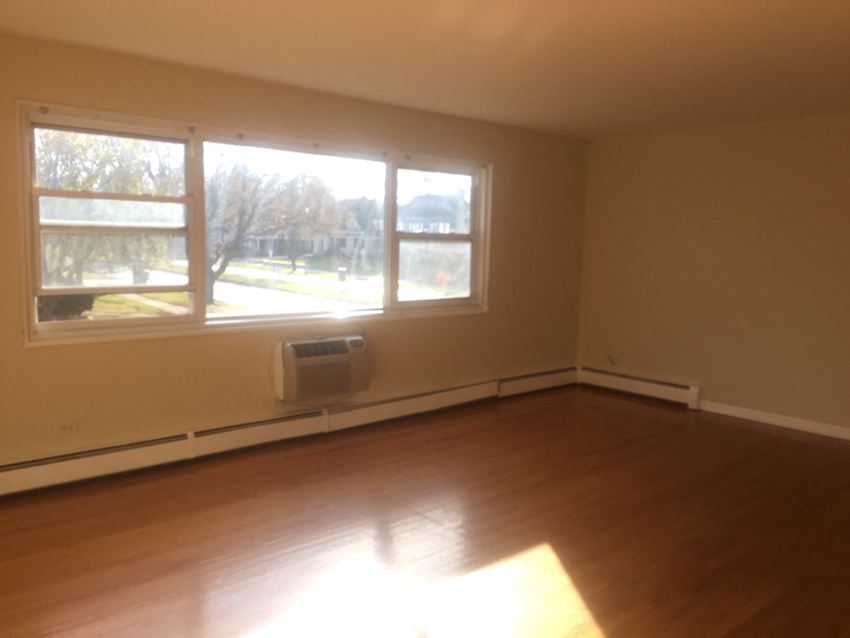 an empty living room with a wood floor and large windows