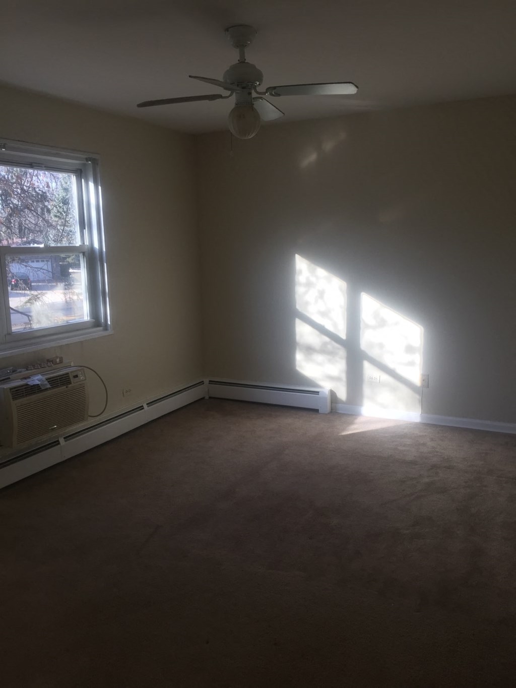 an empty living room with a ceiling fan and a window