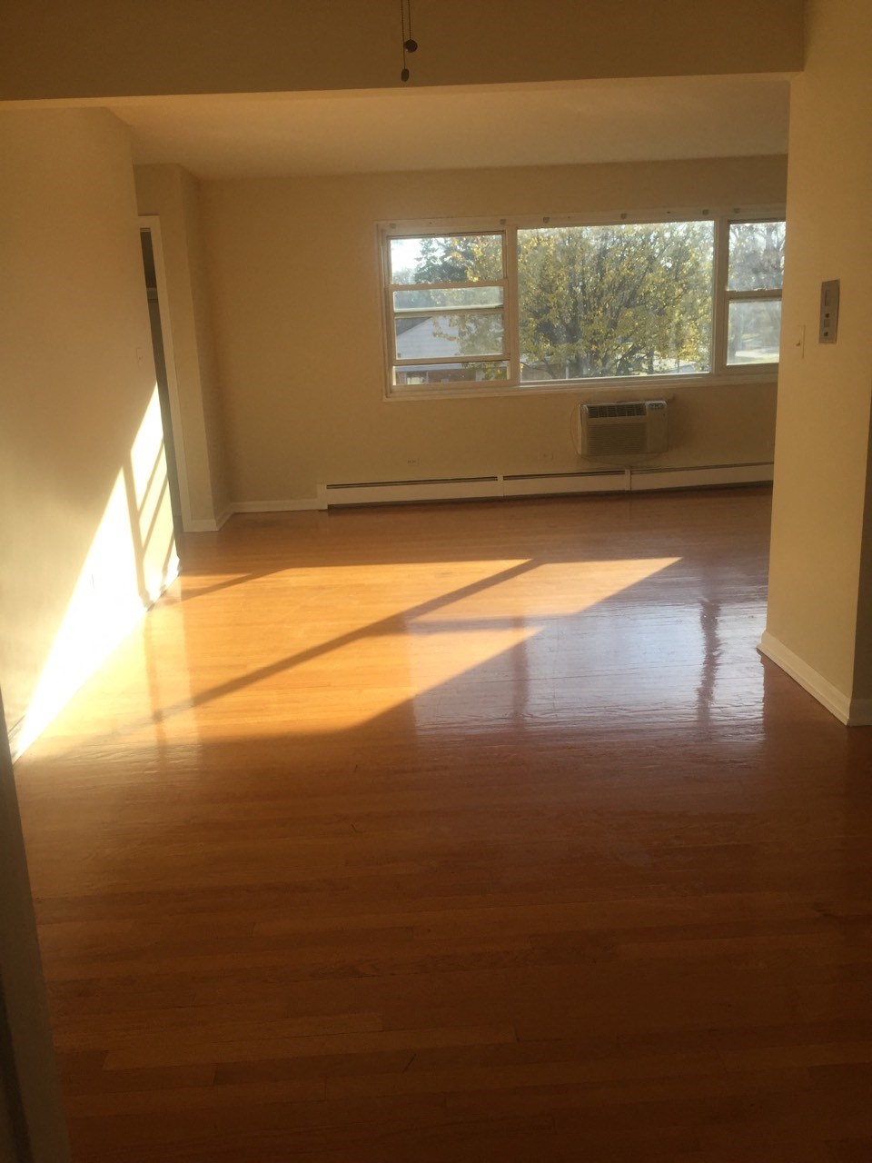 an empty living room with wooden floors and a window