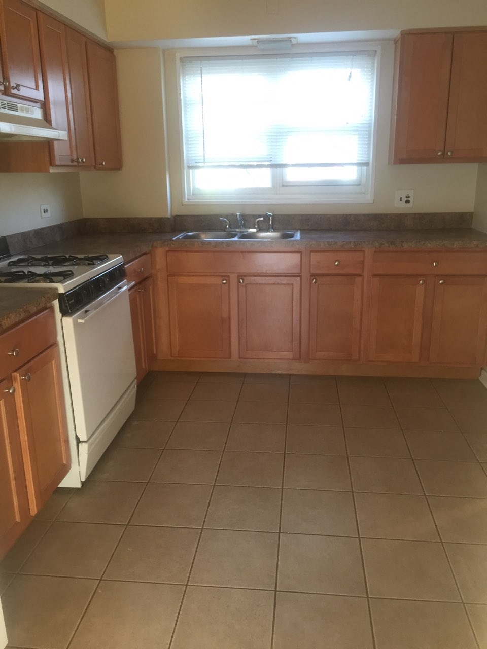 an empty kitchen with wooden cabinets and a window