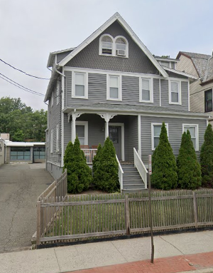 A grey house with a white fence in front.