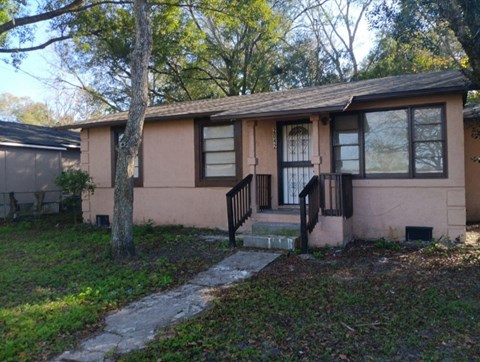 the front of a house with a porch and a tree