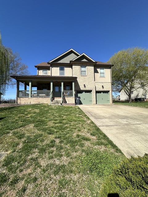 a large brick house with a driveway and a porch